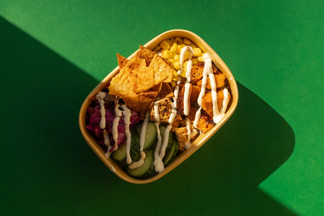 Een bowl met mais, zoete aardappel, rode kool, komkommer en krokante wraps